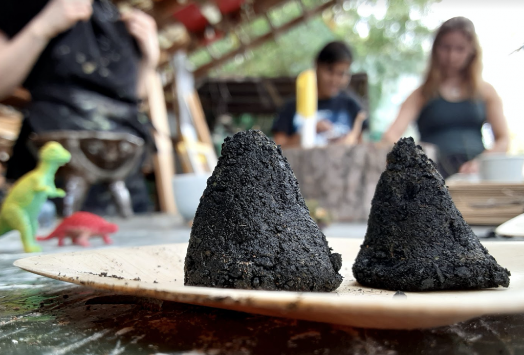 Close up image of two cones of dirt, on a table, students in the blurry background